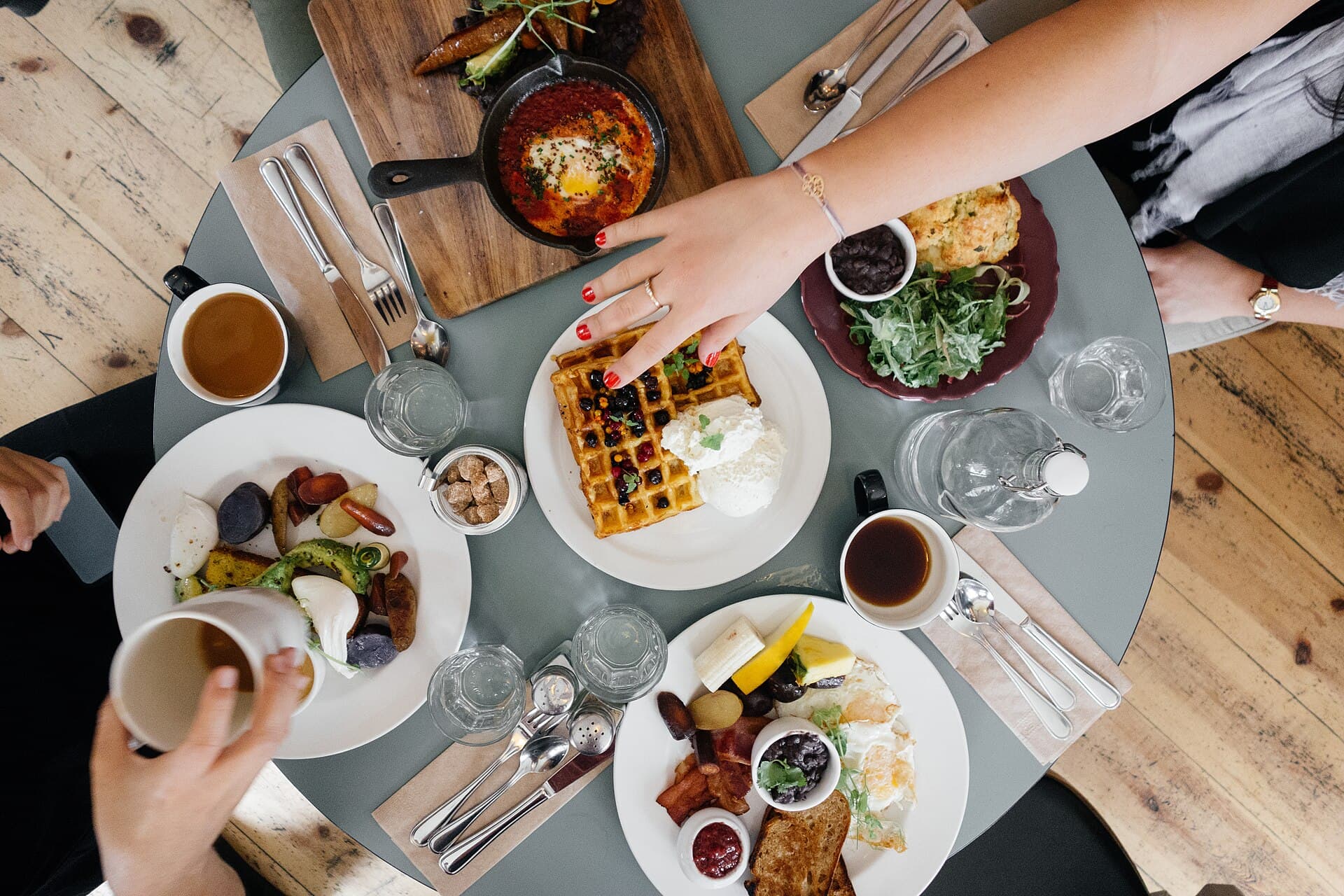 Friends sharing waffles, eggs, coffee, and brunch dishes around a table