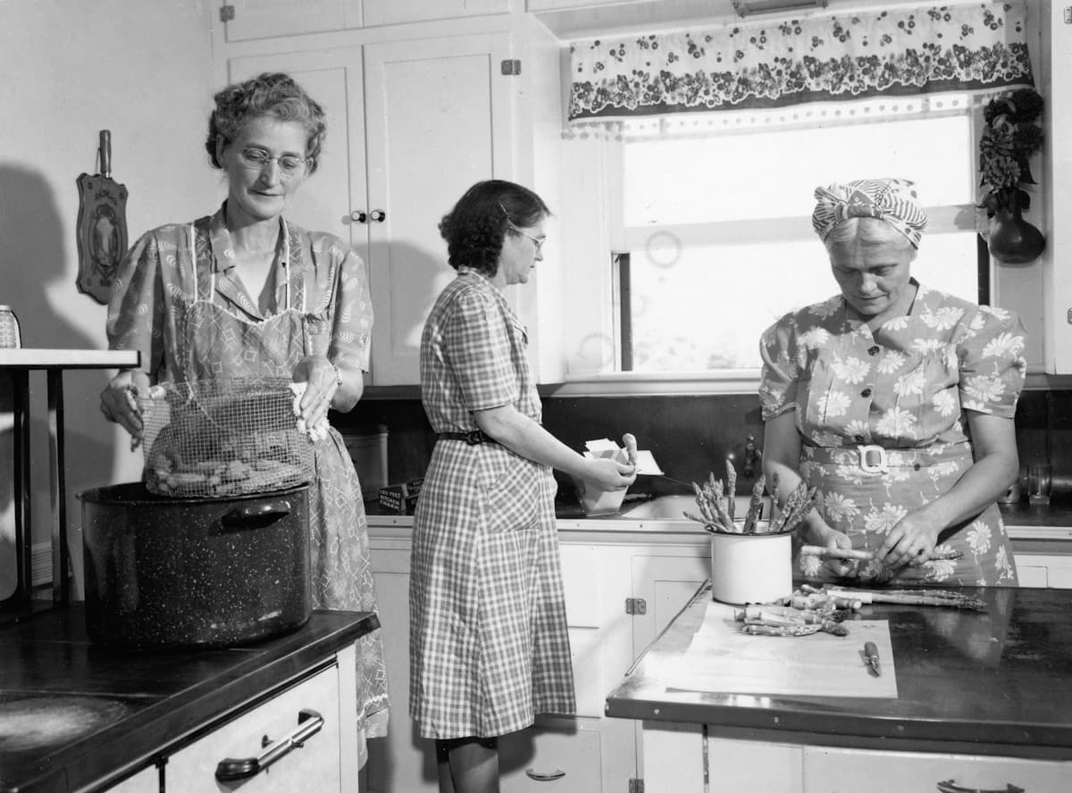 Three women preparing food in a vintage kitchen