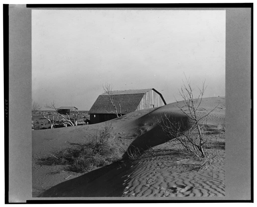 Dust Bowl winds piled large drifts of soil against a farmer barn near Liberal, Kansas